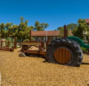 Tractor | Cultivate playground fun with this West Australian Jarrah Tractor, featuring salvaged tyres, stainless steel detailing, bench seat platform with slide, and open engine bay for imaginative farm play. | VRI