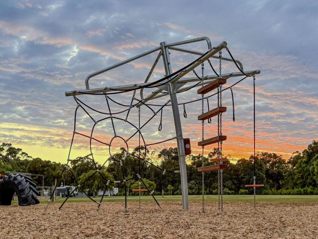 432-CLC Clothesline Climber — full structure at dusk showing spider web rope net and chain-suspended Jarrah rope ladder, commercial playground Dunsborough WA
