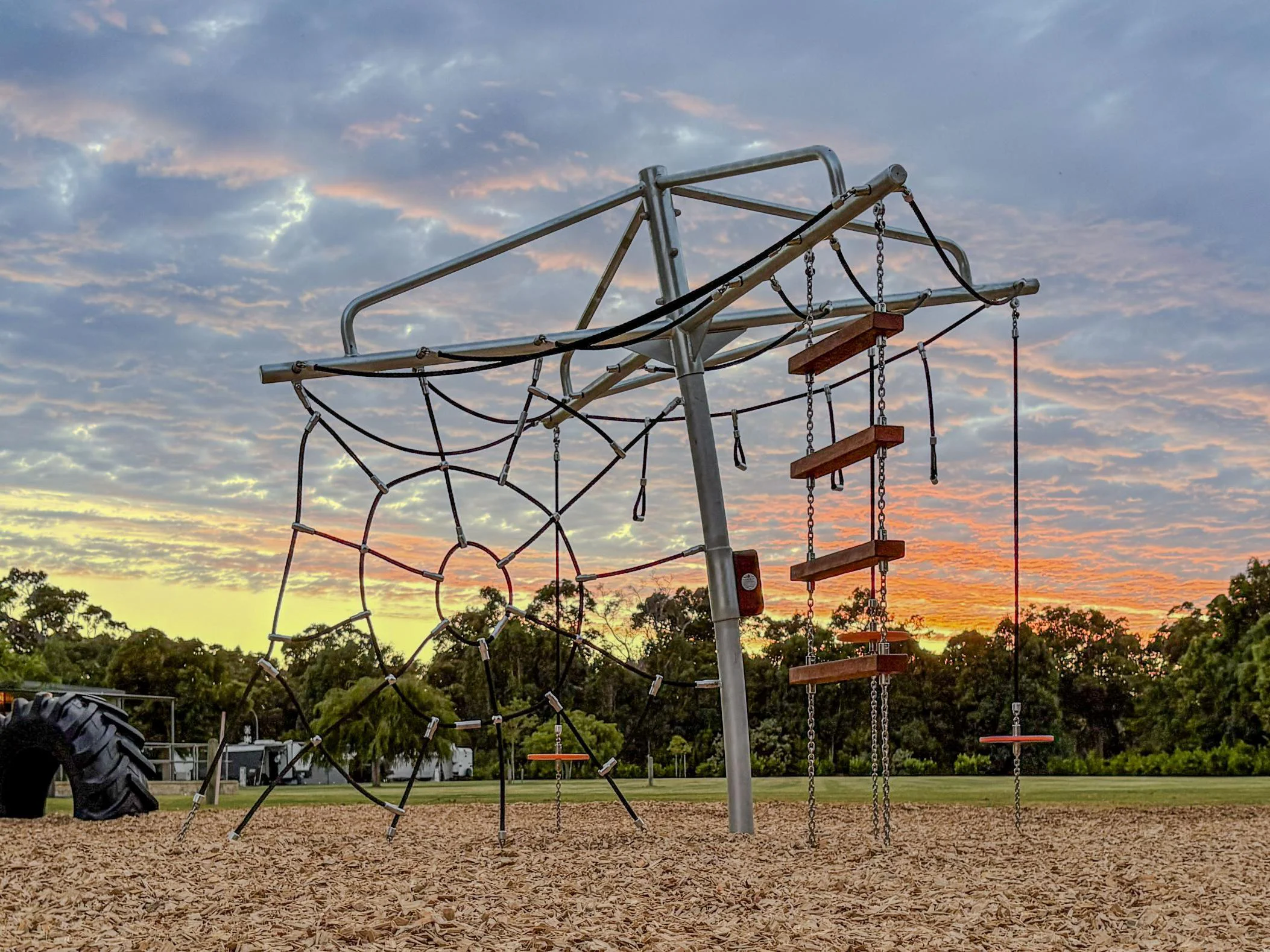 432-CLC Clothesline Climber — full structure at dusk showing spider web rope net and chain-suspended Jarrah rope ladder, commercial playground Dunsborough WA