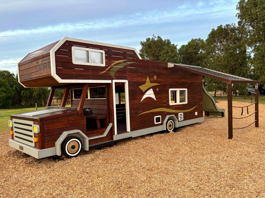 524-MTH Motorhome — front three-quarter view at dusk alongside companion spider web net climber and disc swing equipment, holiday park Dunsborough WA