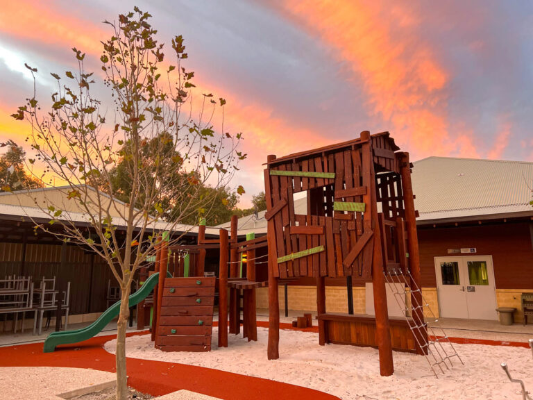 Charlie's Paddock playground at sunset with custom treehouse cubby and timber ute in warm golden light at Piara Waters