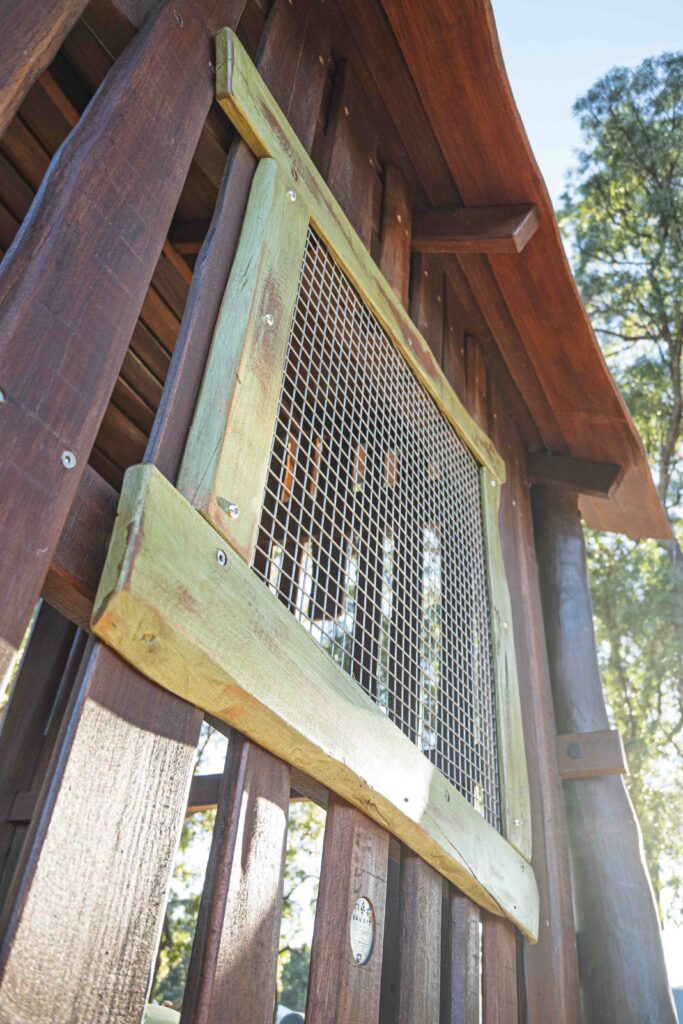 Interior detail of Jarrah timber cubby shack showing board cladding mesh panel and steel cable bracing at Hathaway Reserve playground Baldivis