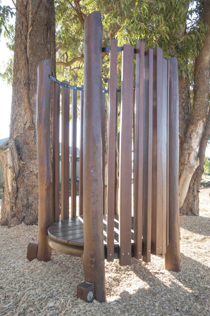 Circular Jarrah bushpole pod enclosure with aluminium top ring and elevated timber deck at Hathaway Reserve playground Baldivis