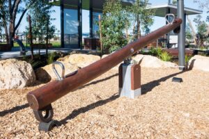 Jarrah timber see saw with stainless steel handles and rocking mechanism among landscaping rocks at Baldivis Parks Stage 17 playground