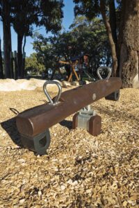 Jarrah timber mini see saw with stainless steel pivot mechanism on bark mulch at Hathaway Reserve playground Baldivis