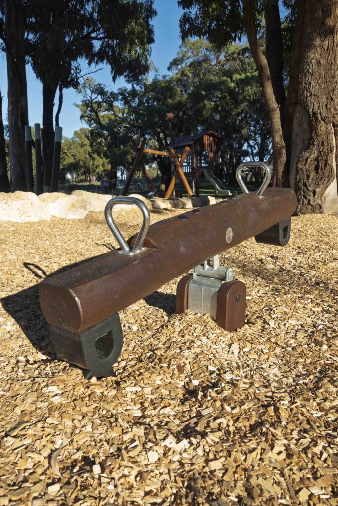 Jarrah timber mini see saw with stainless steel pivot mechanism on bark mulch at Hathaway Reserve playground Baldivis