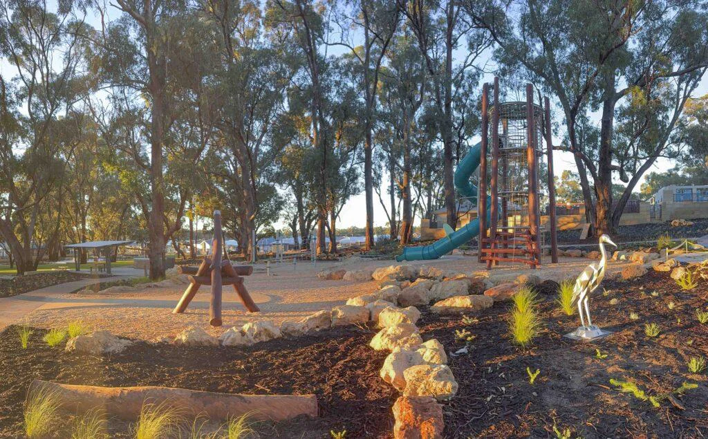 Jarrah timber playground with climbing tower tube slide and nature play equipment under mature trees at Hathaway Reserve Baldivis