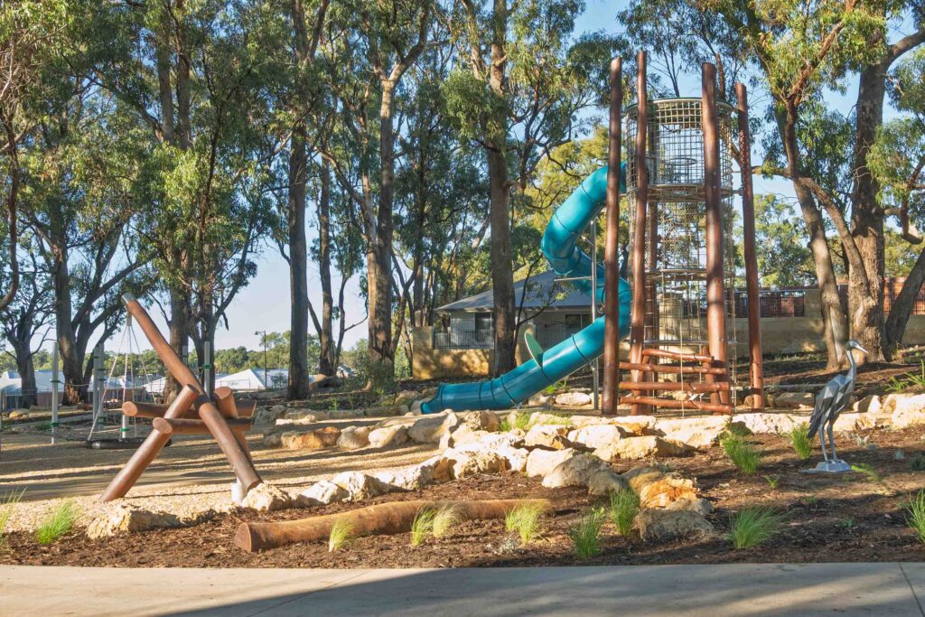 Jarrah timber climbing tower visible through mature tree canopy at Hathaway Reserve nature playground Baldivis