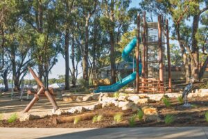 Jarrah timber climbing tower visible through mature tree canopy at Hathaway Reserve nature playground Baldivis