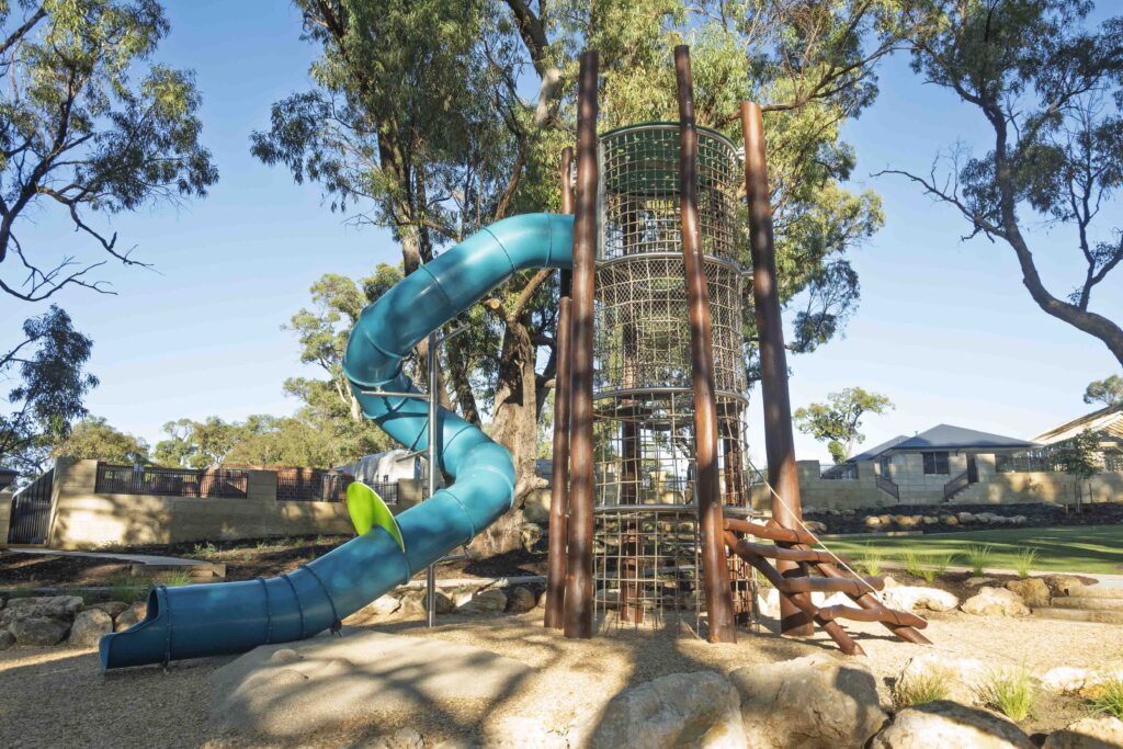 Wide angle view of Jarrah timber playground featuring climbing tower with teal tube slide at Hathaway Reserve Baldivis