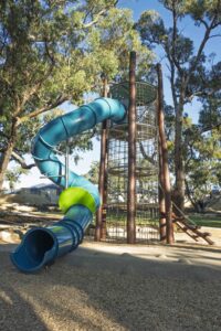 Jarrah climbing tower with teal tube slide and painted stilt steppers at Hathaway Reserve playground Baldivis