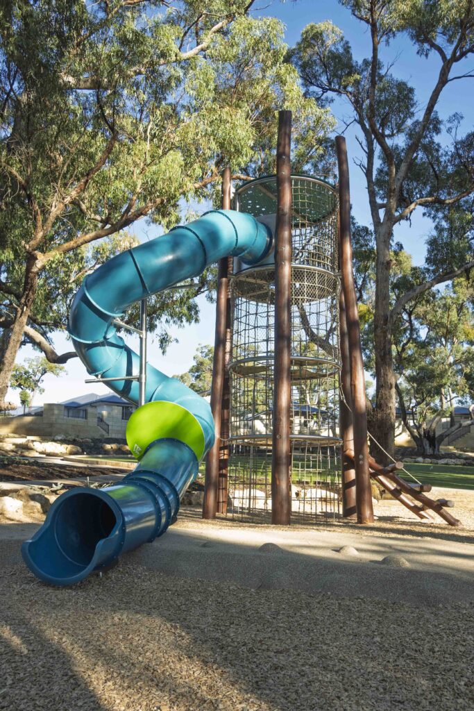 Jarrah climbing tower with teal tube slide and painted stilt steppers at Hathaway Reserve playground Baldivis