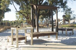 Timber shelter structure with bench seating alongside sand play area at Hathaway Reserve playground Baldivis
